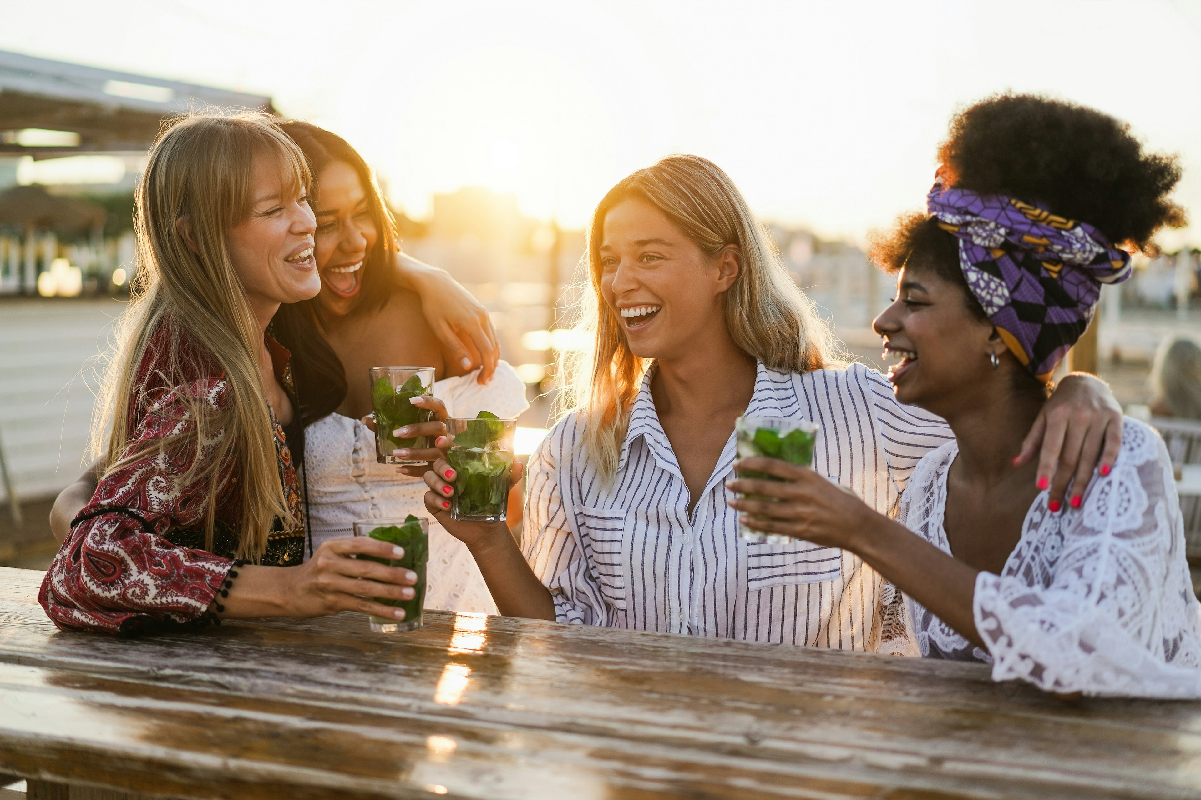 Happy girls having fun drinking cocktails at bar on the beach