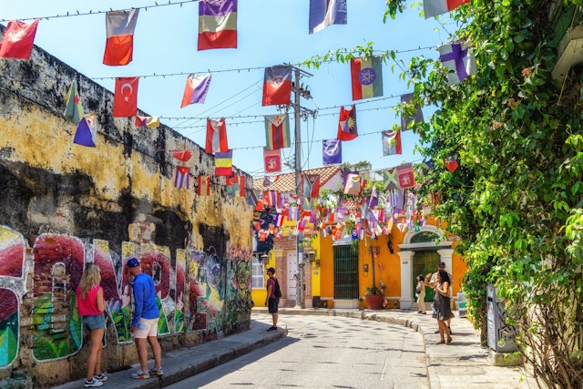 Tourists stop to look at street art and murals that cover the walls of a colorful neighborhood