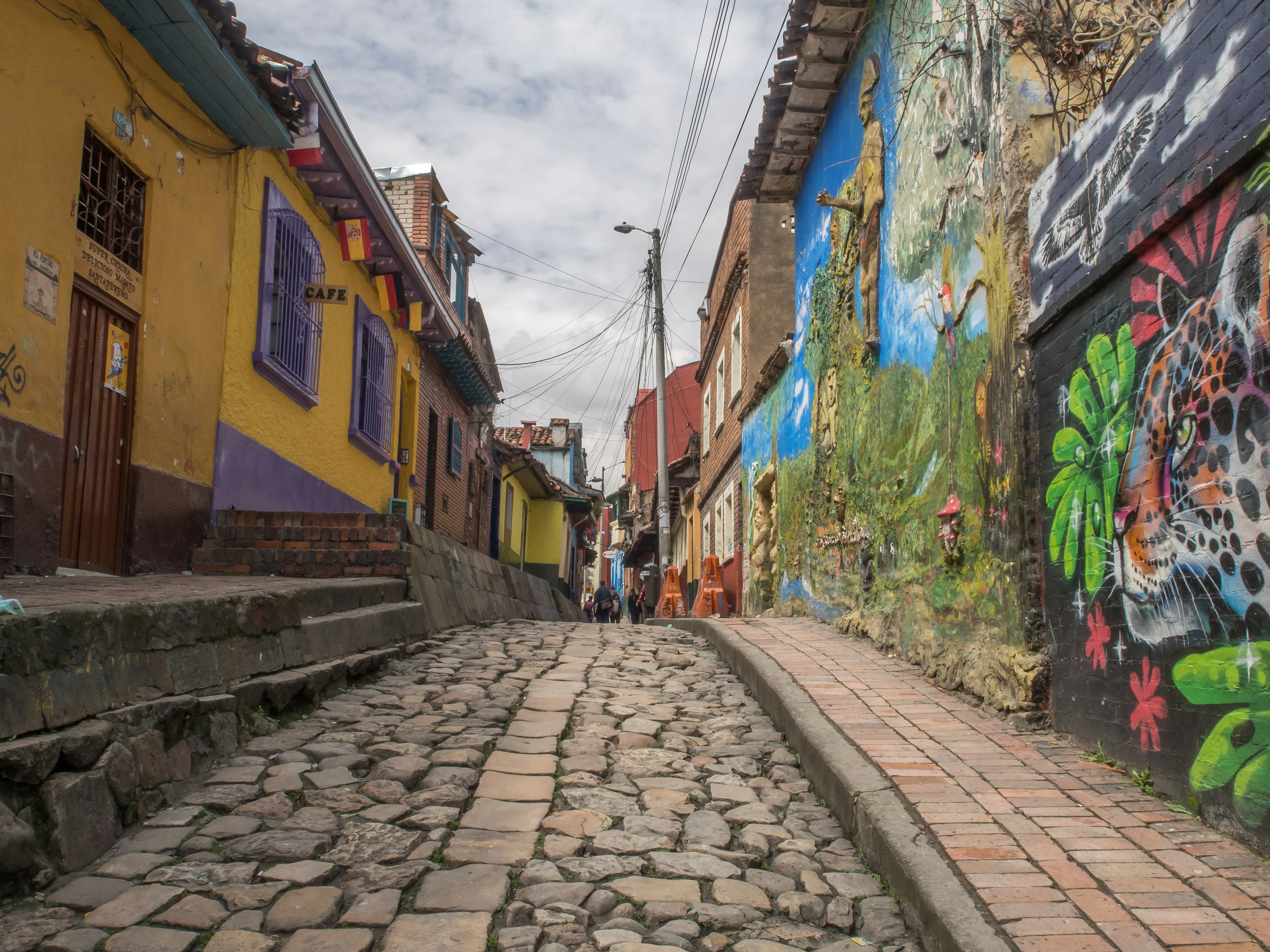 A narrow cobbled street lined with colorful artworks