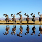 BAYAN-ULGII, MONGOLIA - SEP 26: Senior mongolian horsemen in traditional kazakh clothing show standing steppe reflecting in water on morning with golden eagle of village sagsai on September 26, 2016; Shutterstock ID 585027838; your: Claire Naylor; gl: 65050; netsuite: Online ed; full: Mongolia when to go
585027838