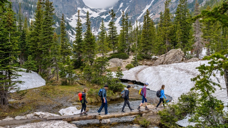 Estes Park, Colorado, USA - June 24, 2017: On a foggy spring day, a group of hikers walking cross a tree trunk bridge over Tyndall Creek on Emerald Lake Trail at base of Hallett Peak and Flattop Mtn.
708951949