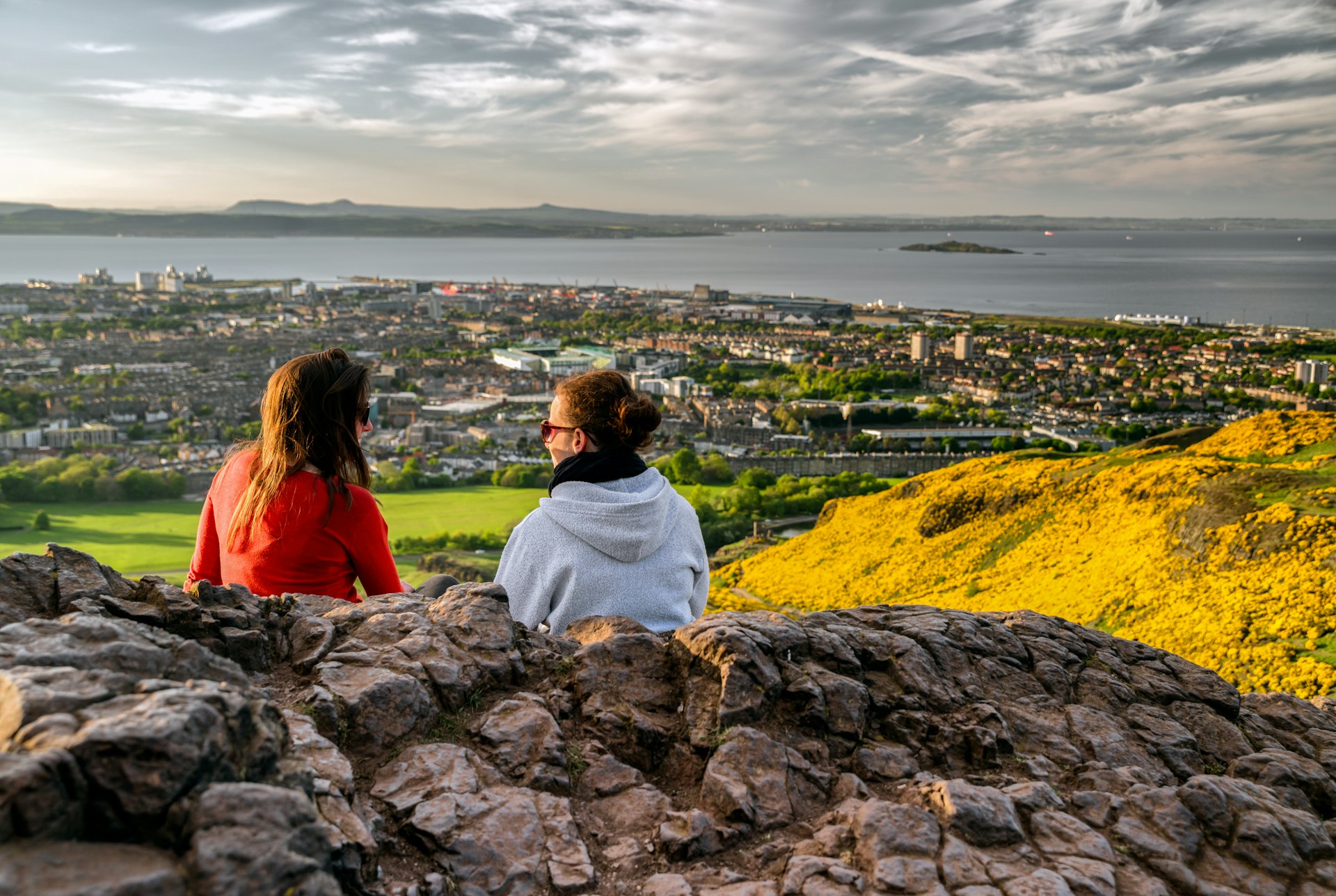 Girls sitting on the hill of Arthur’s Seat overlooking Edinburgh, Scotland, UK