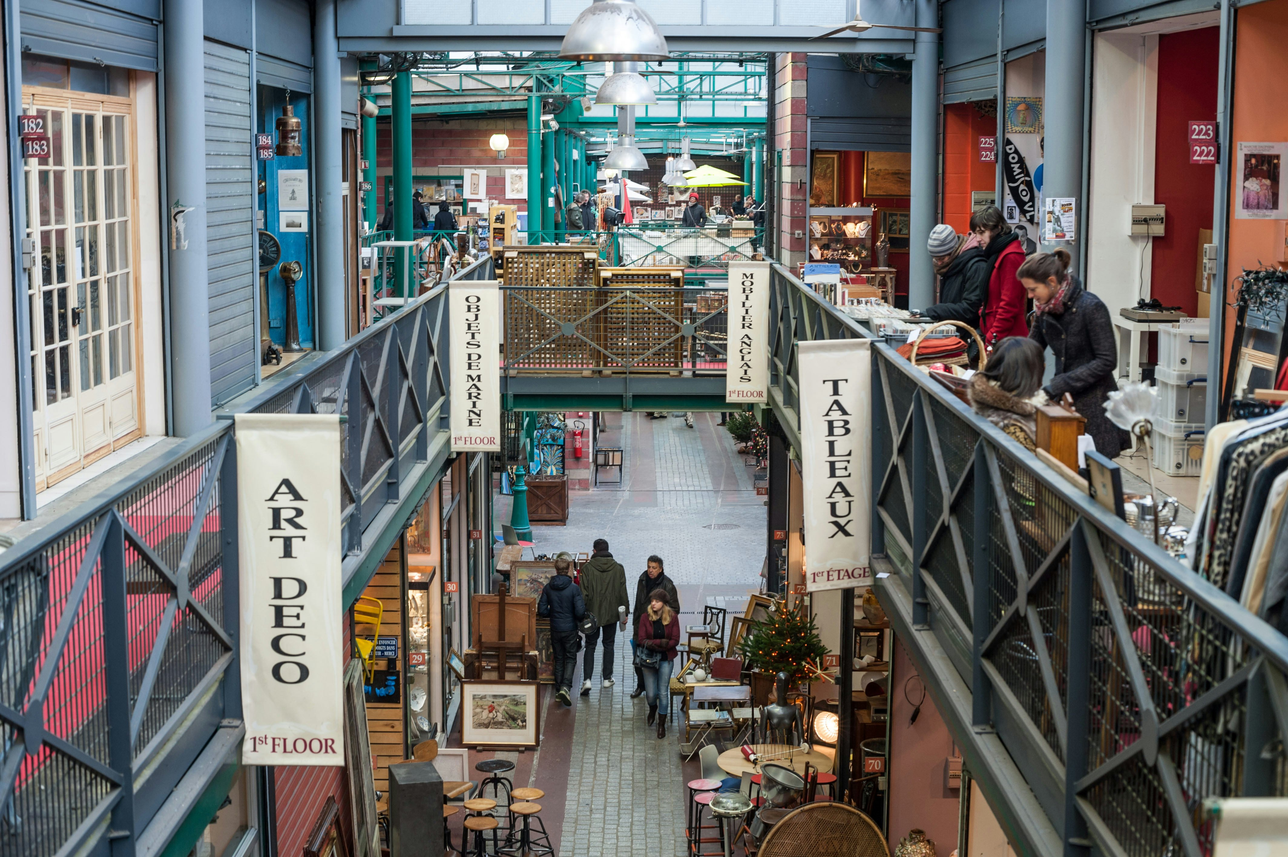 Many people are wandering around a galleried flea market, with stalls selling a variety of vintage goods over two floors