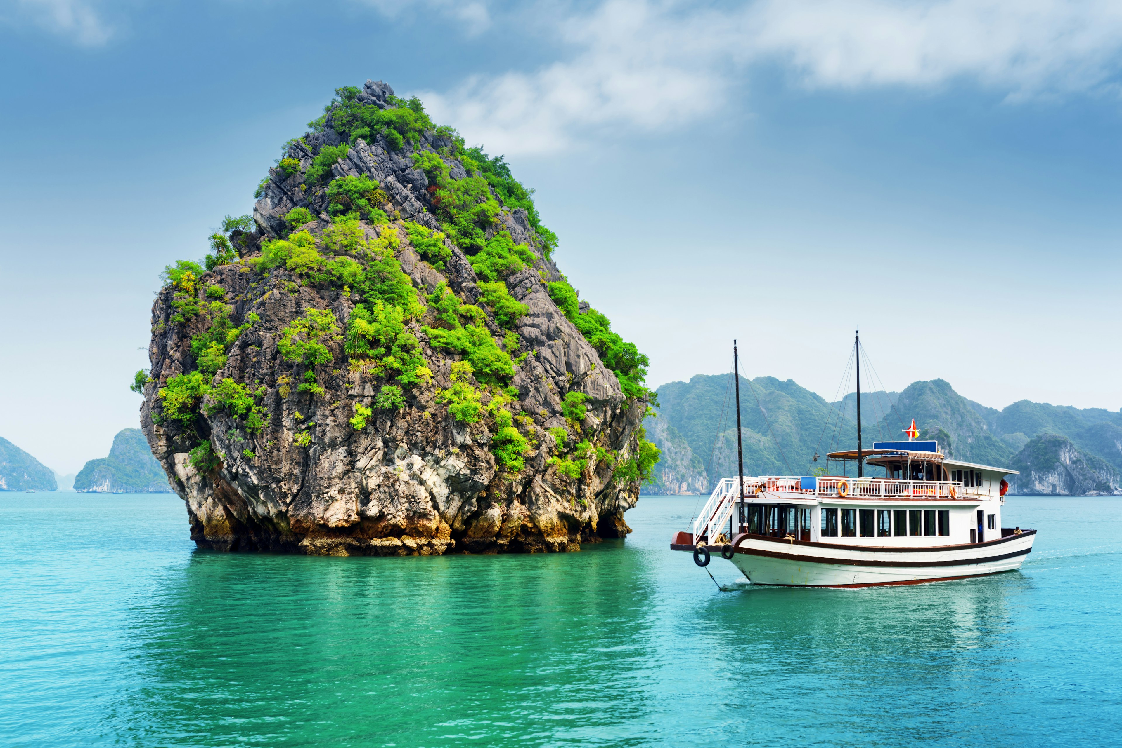 A boat moored in turquoise waters near a karst outcrop