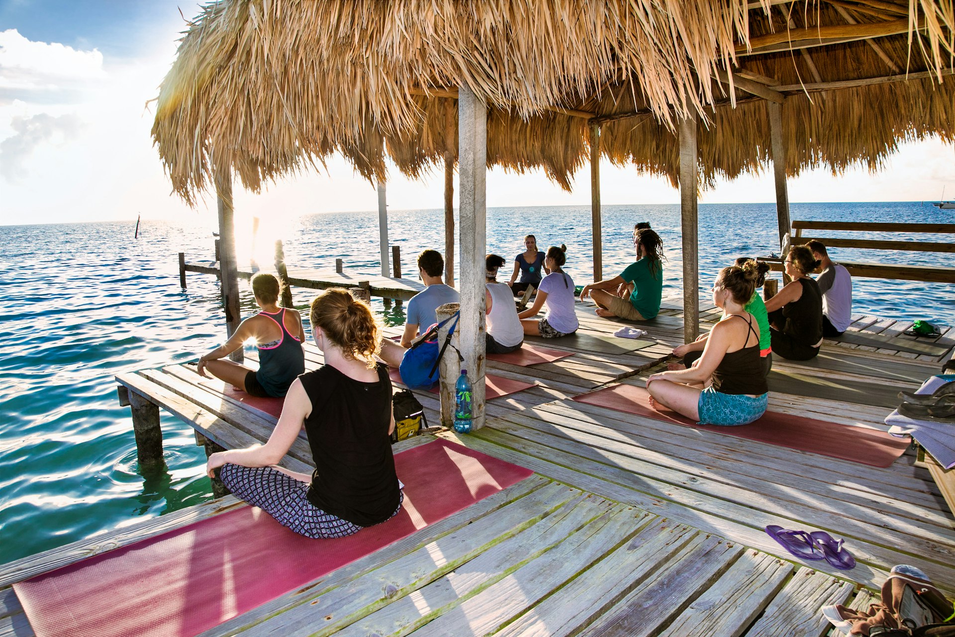 Yoga at dock of Caye Caulker island. Participants perform yoga moves outdoors by the sea.