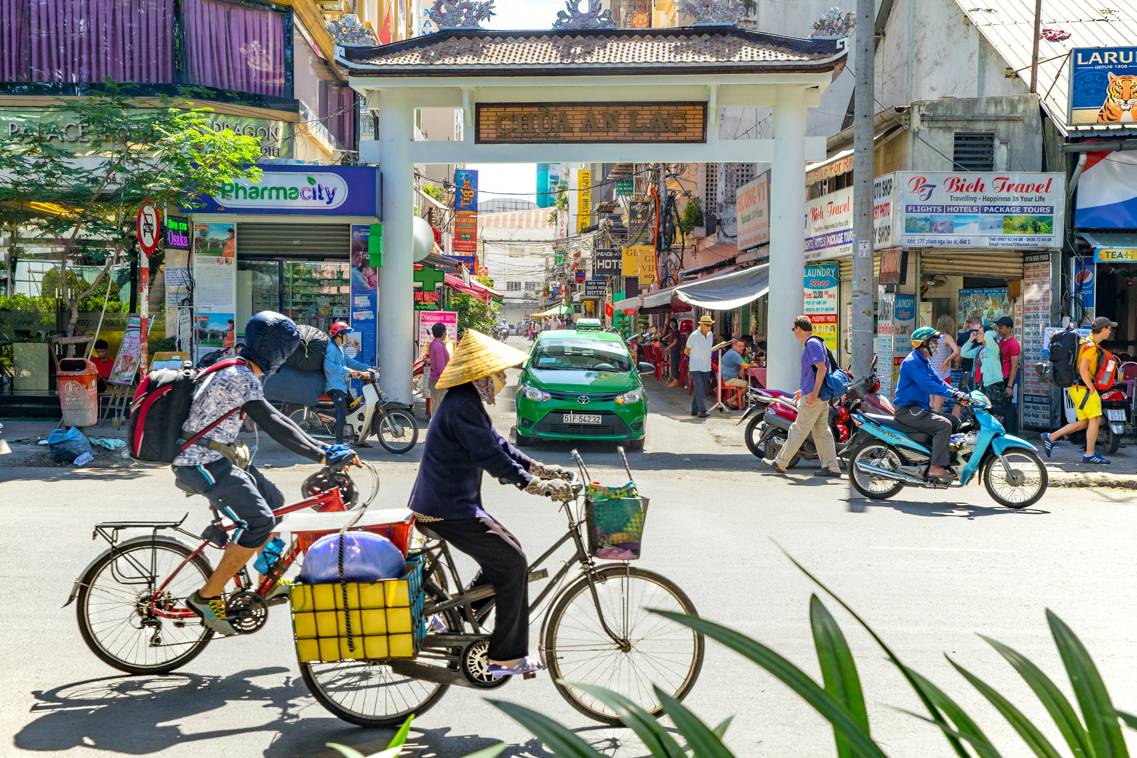 Cyclists and pedestrians on a street lined with tourist offices and shops