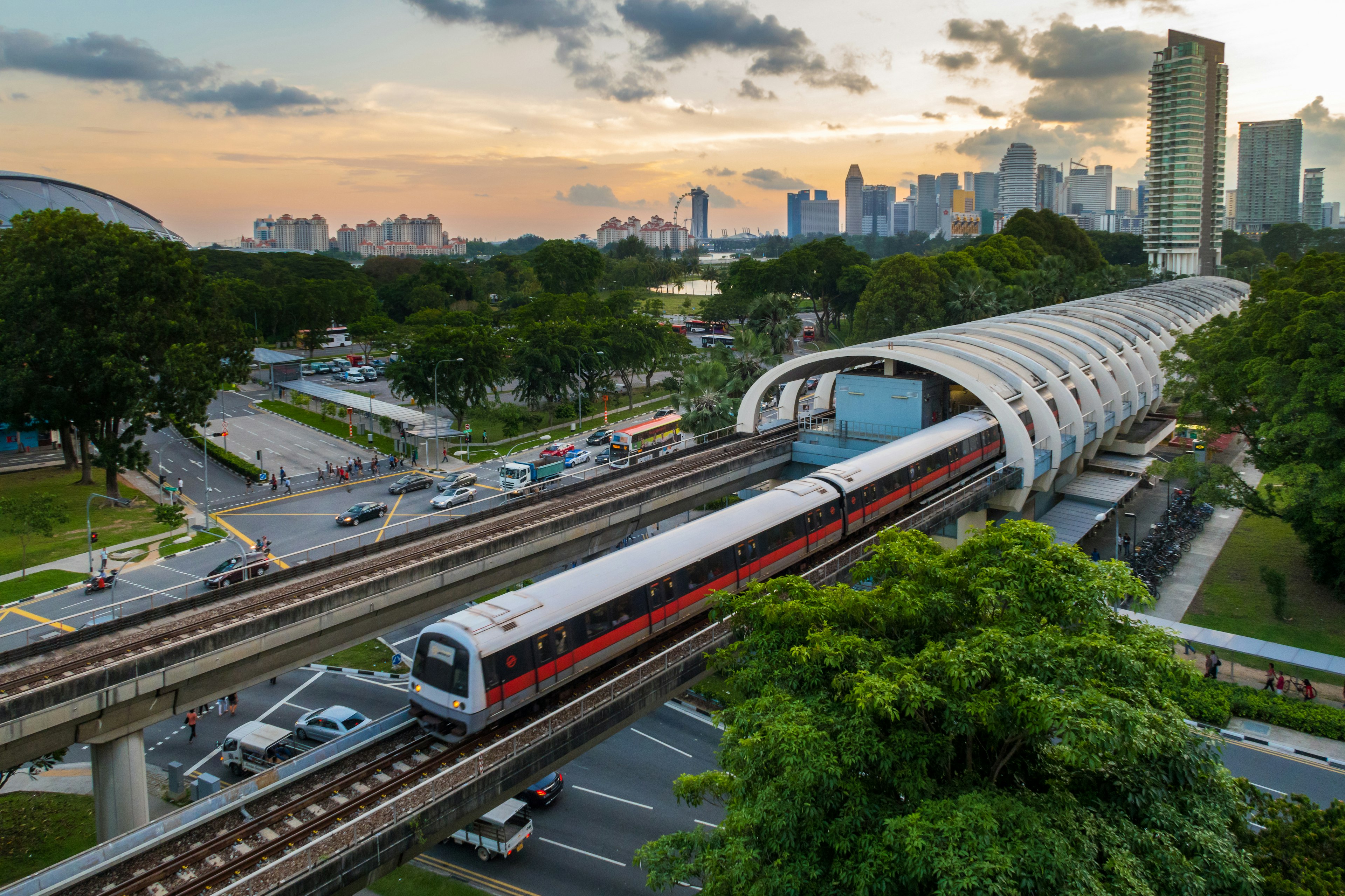 A metro train leaves a station with a cityscape behind