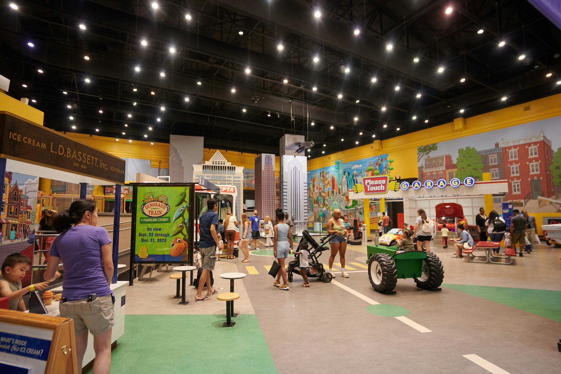 Families with young children play on trucks and interact with exhibits in a museum