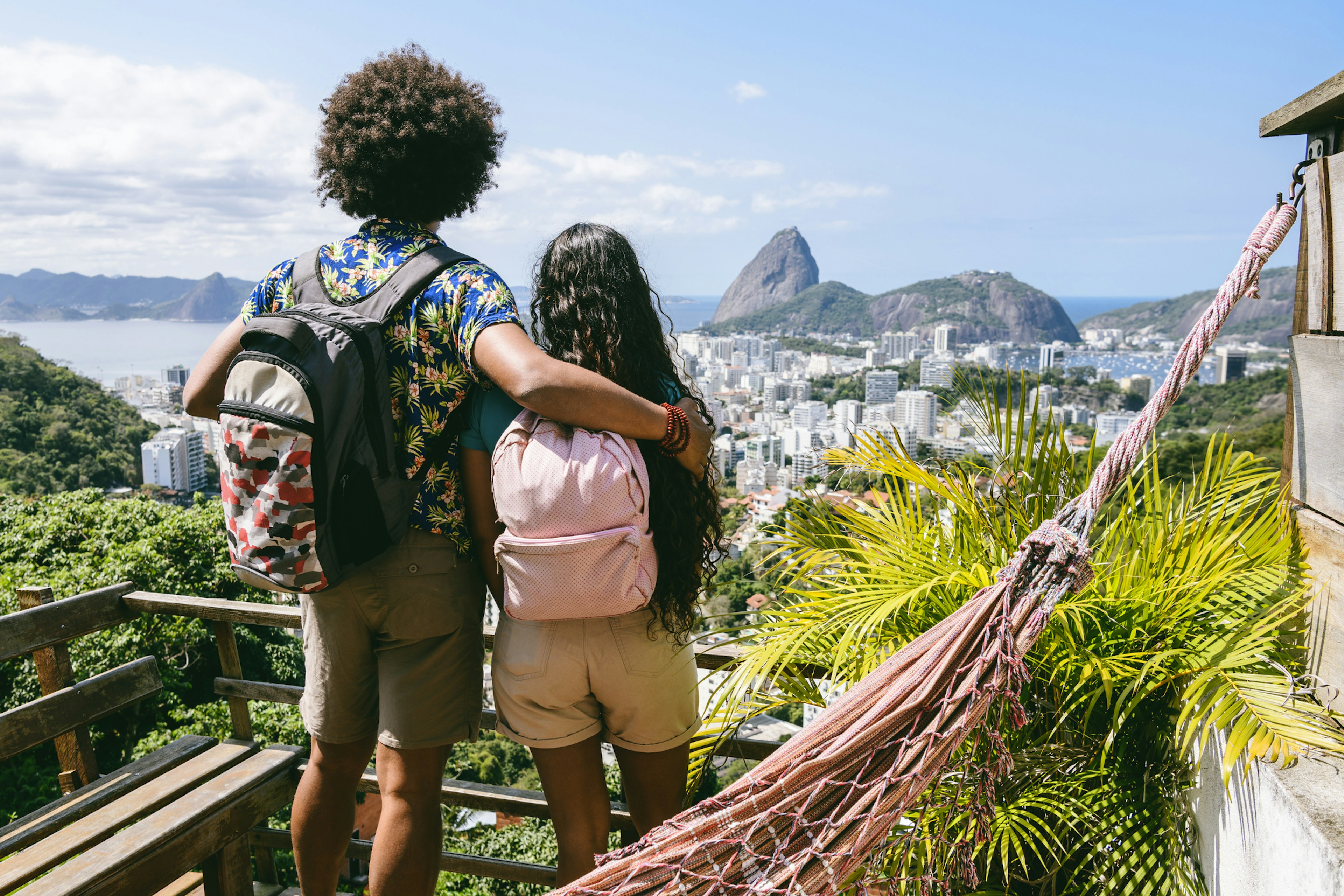 Man and woman wearing backpacks, looking at city scape, elevated view from balcony, on vacation