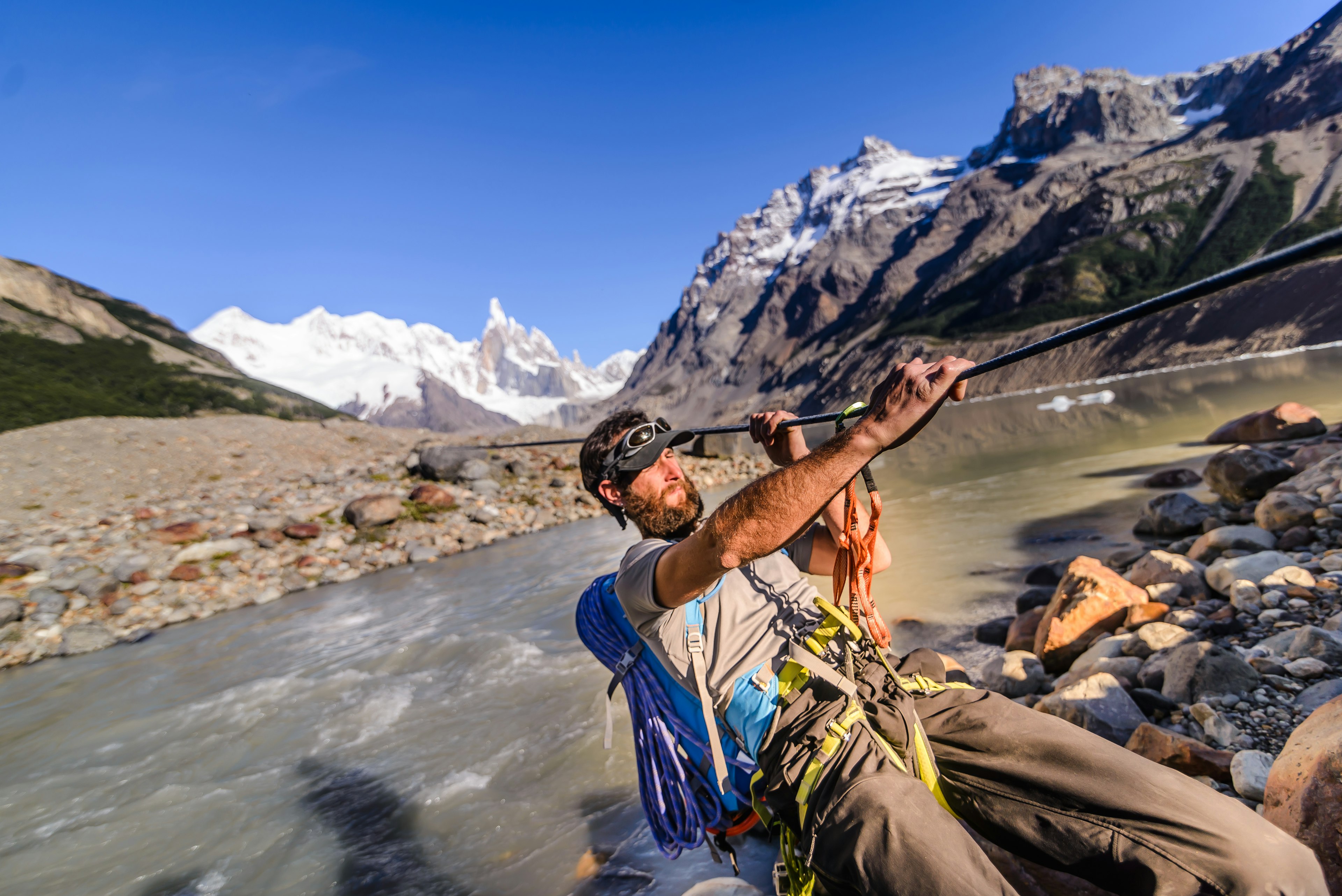 Rock climber sliding on a rope over a river in El Chaltén, southern Patagonia, Argentina