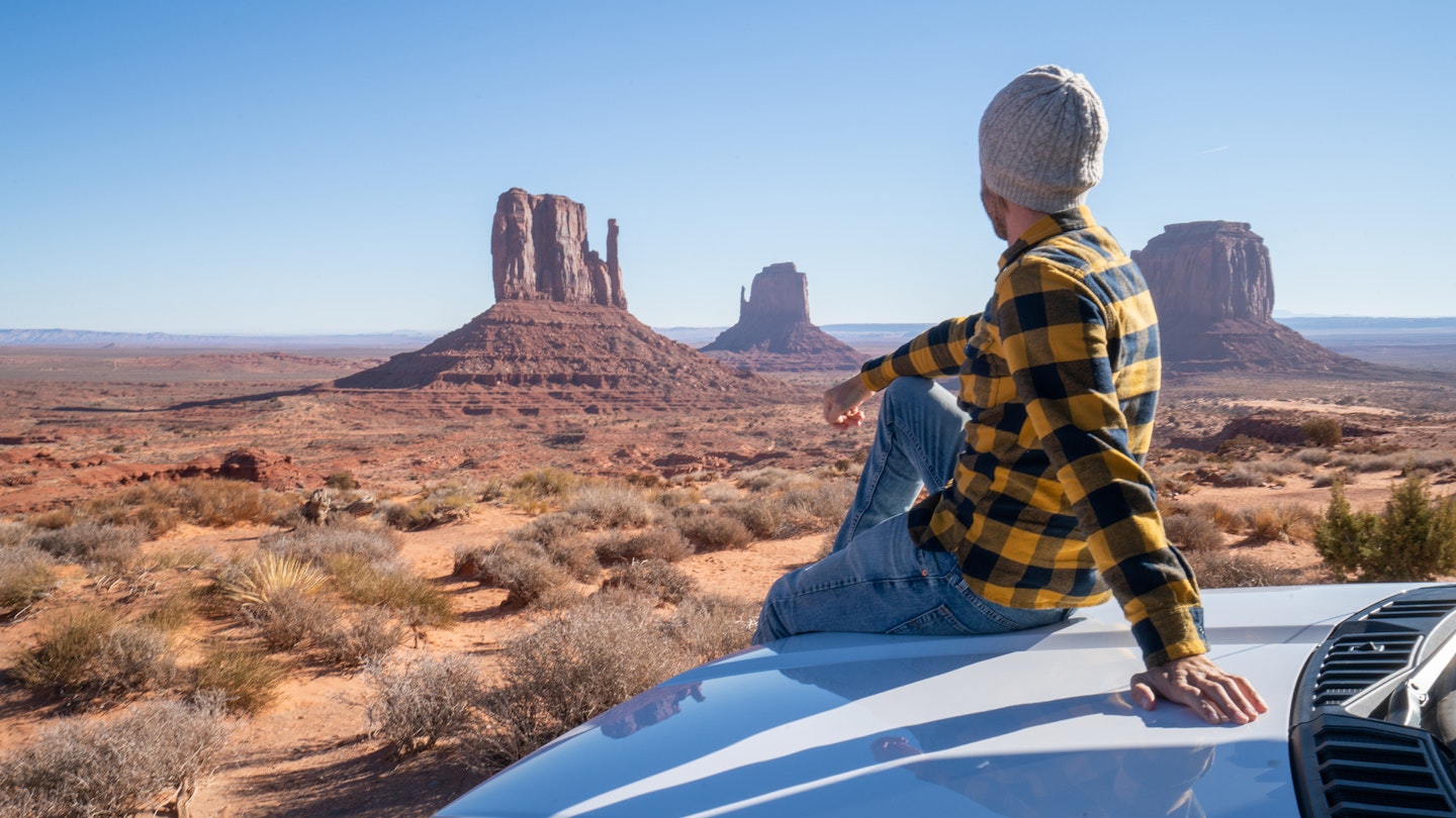 A man sitting on the bonnet of his car looking at the scenery in Arizona
