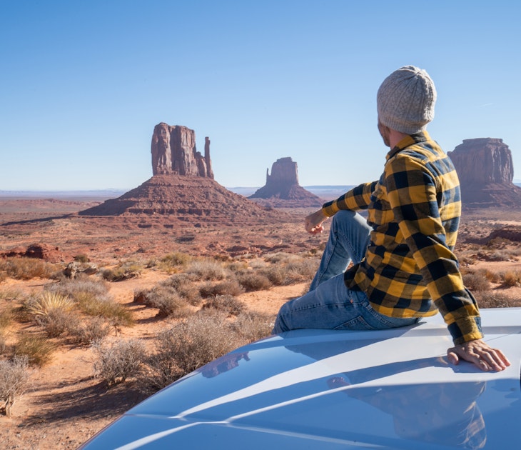 A man sitting on the bonnet of his car looking at the scenery in Arizona