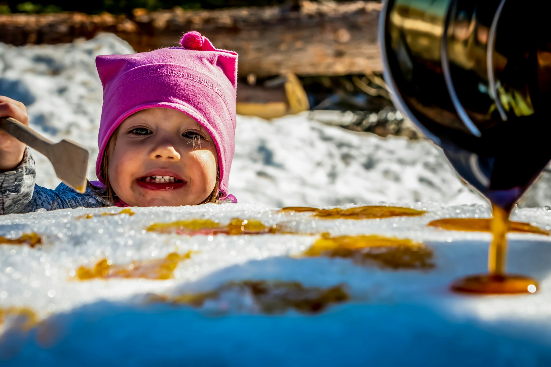 Little girl eating maple syrup on snow at a sugar shack in Québec, Canada