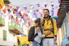 A man and woman embracing and laughing as they walk along a city street in Colombia