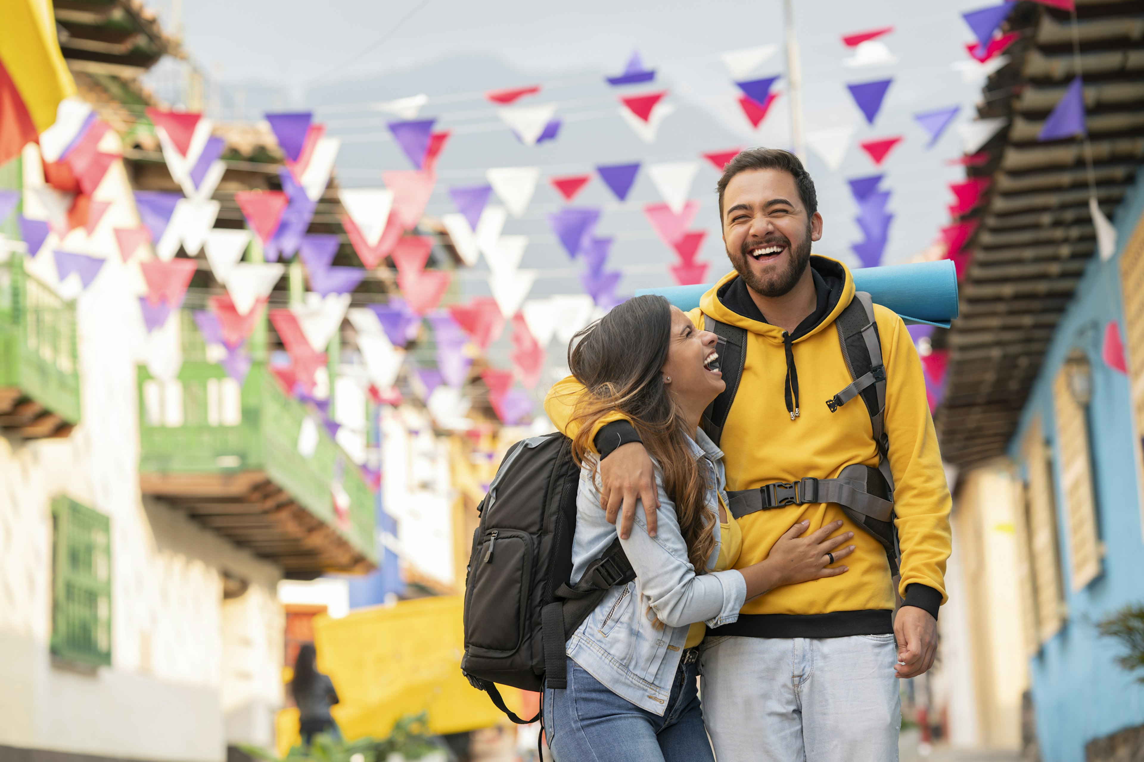 A man and woman embracing and laughing as they walk along a city street in Colombia