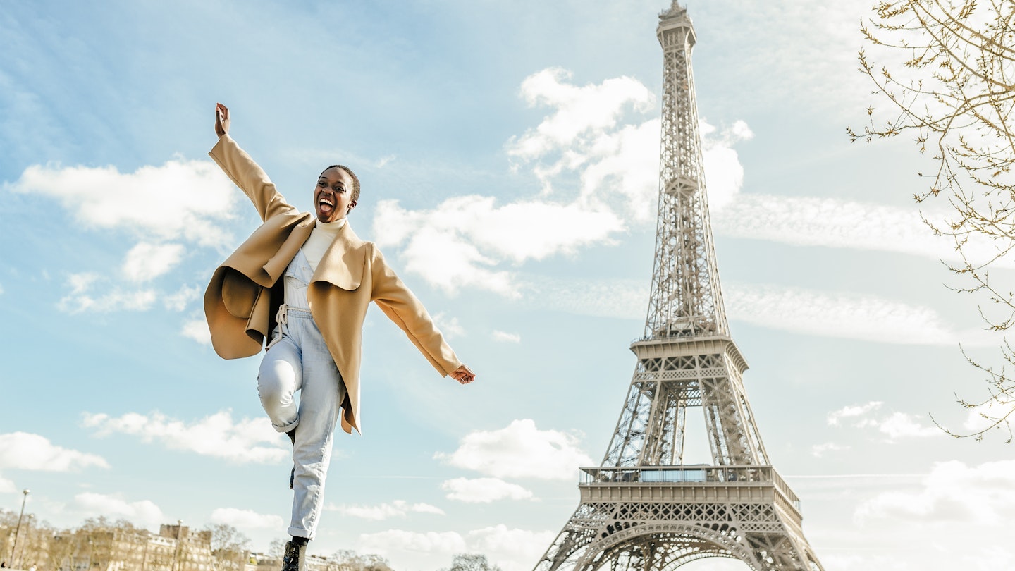 A Black woman dancing near the Eiffel Tower in Paris