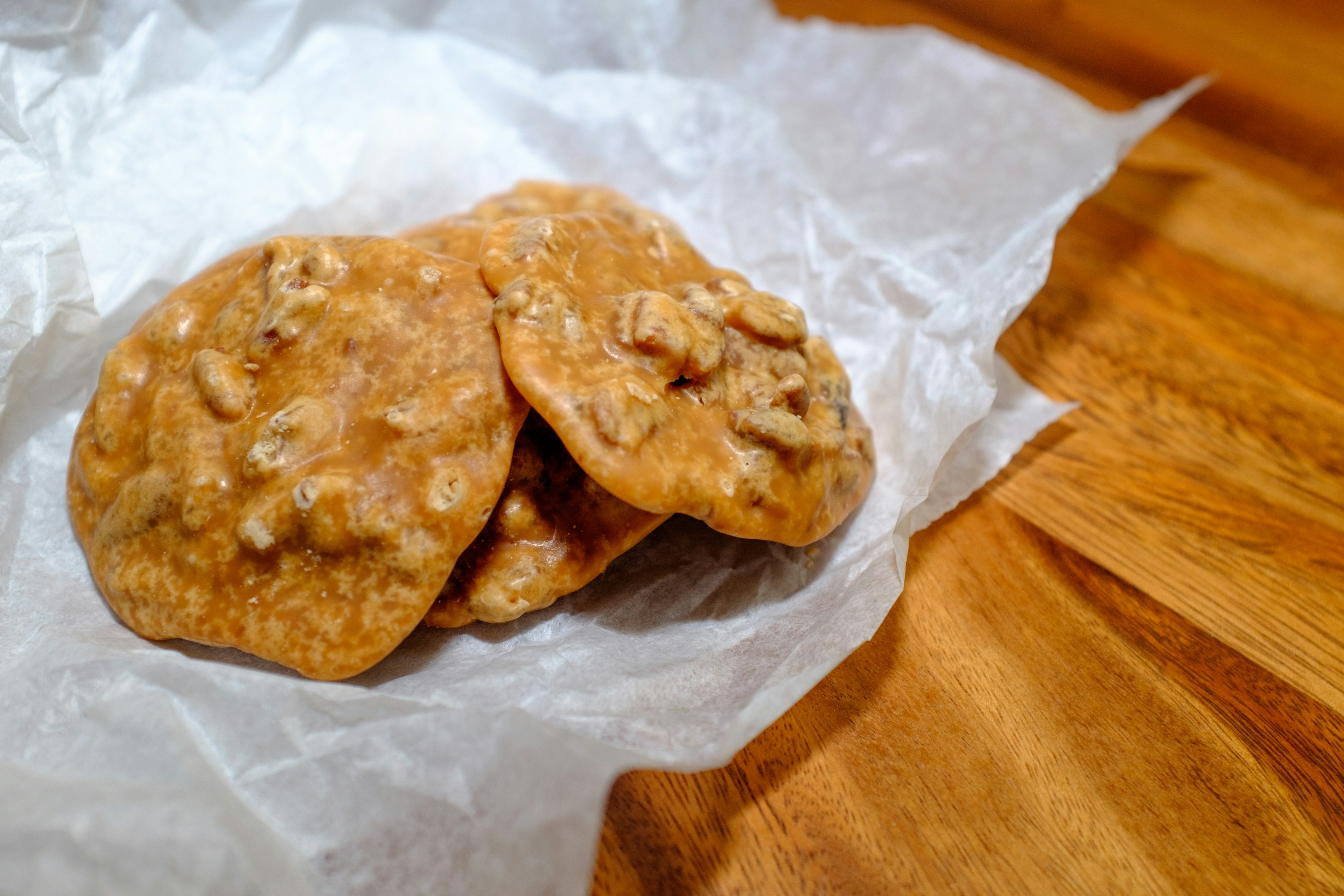 Three caramel-colored pralines sit in pastry paper