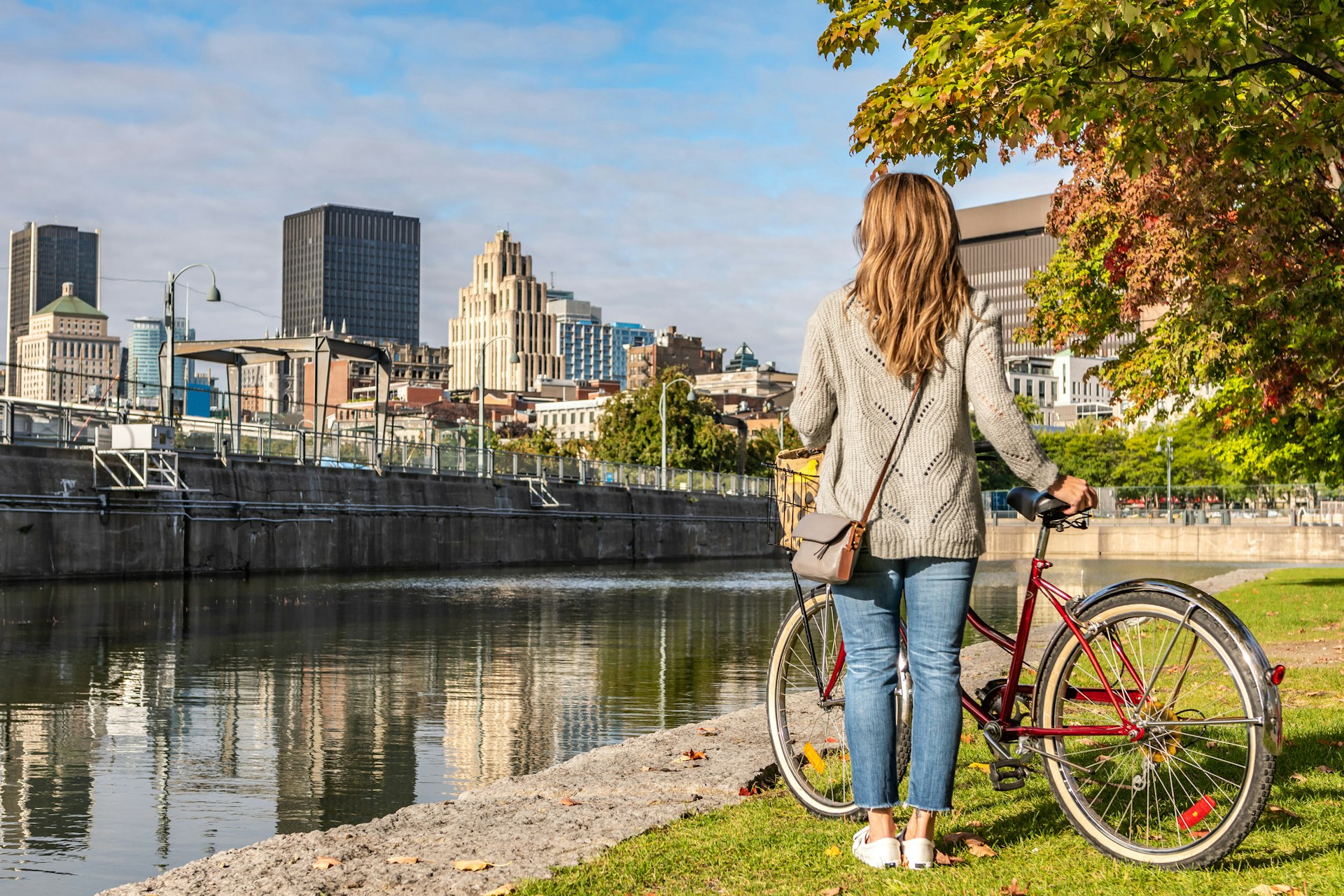 A woman with a bike looking across the river at Montréal's old town.