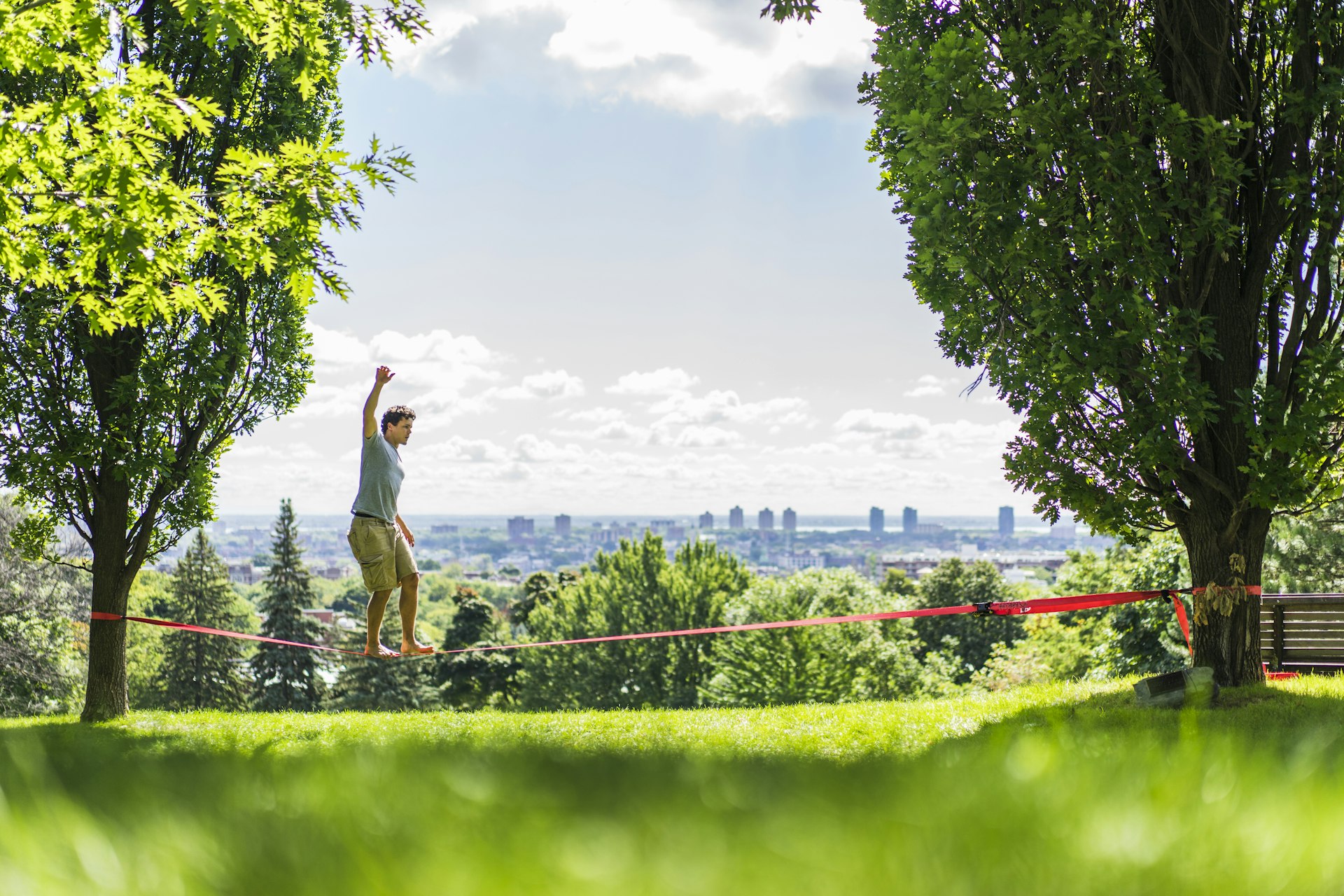 A man practising slacklining in a park overlooking Montreal's skyline