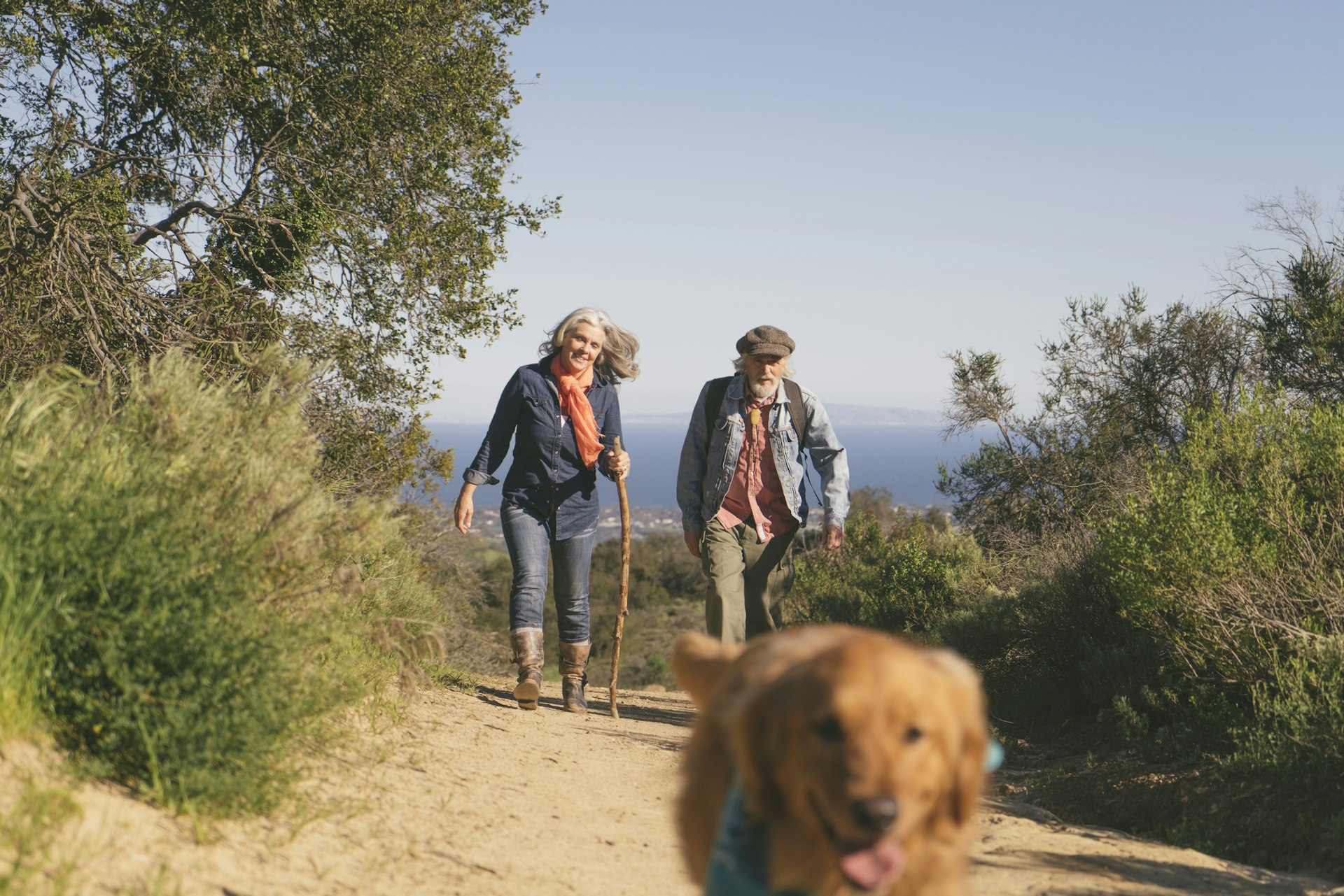 A middle aged woman and man walk along the Solstice Canyon in LA's Santa Monica Mountains following their labrador dog