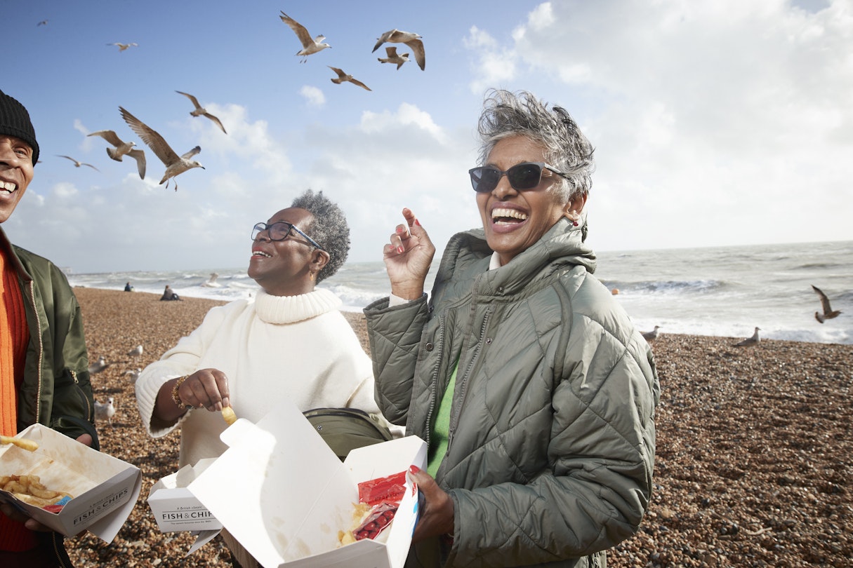 Cheerful male and female friends having french fries at beach on sunny day
1356178617
Three friends on Brighton beach, laughing and eating chips while seagulls circle them