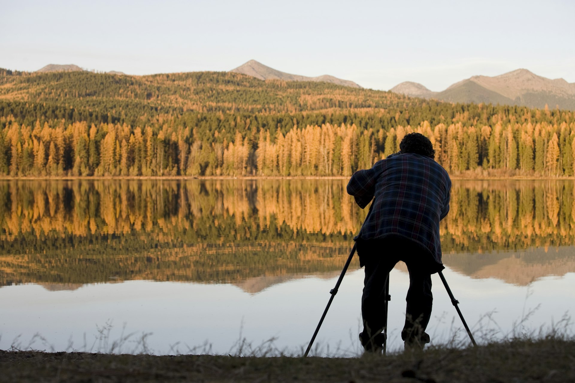 A man takes photos of fall foliage along the shore of Seeley Lake in Montana