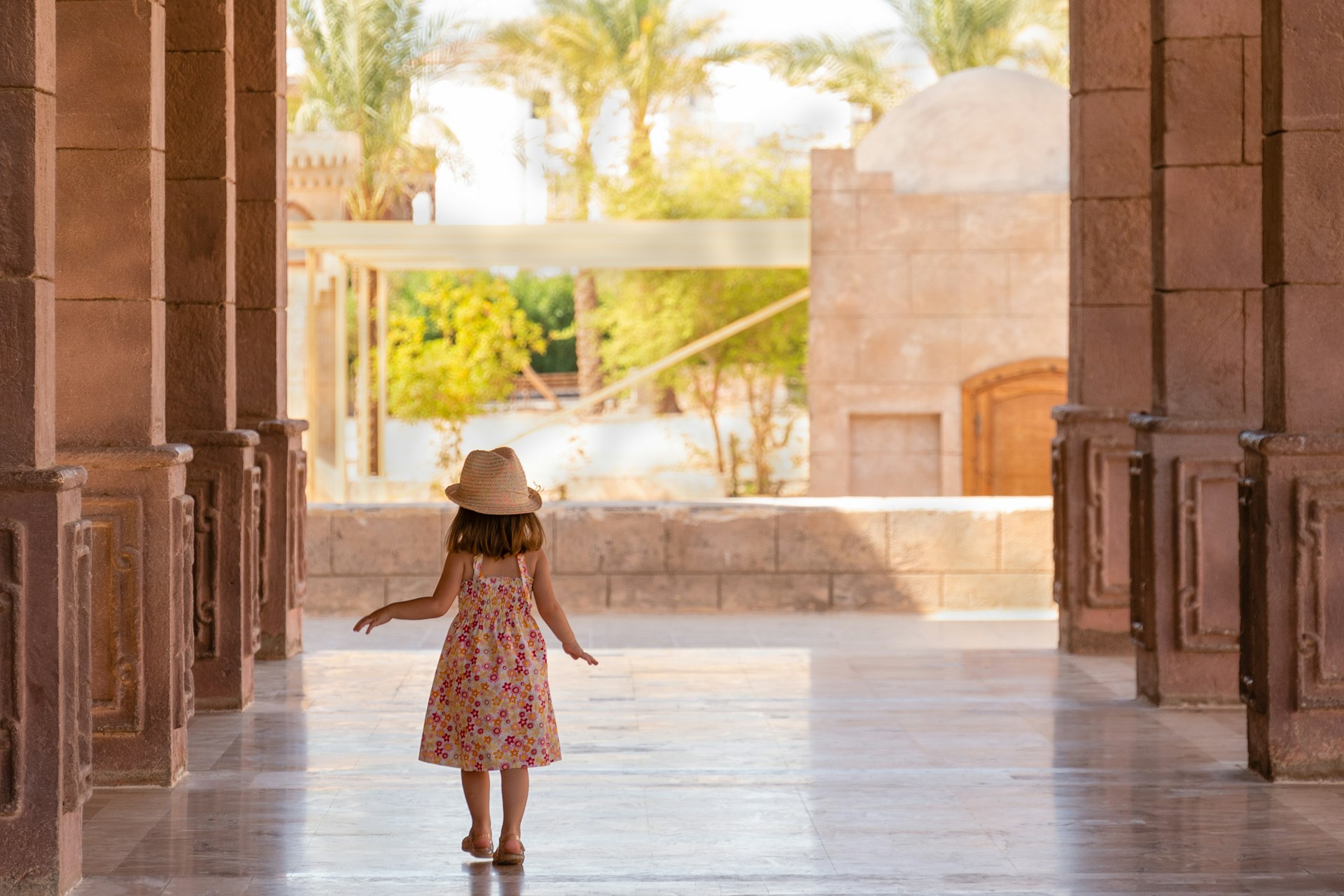 A little girl walks down a portico among the columns in Sharm El Sheikh, Egypt