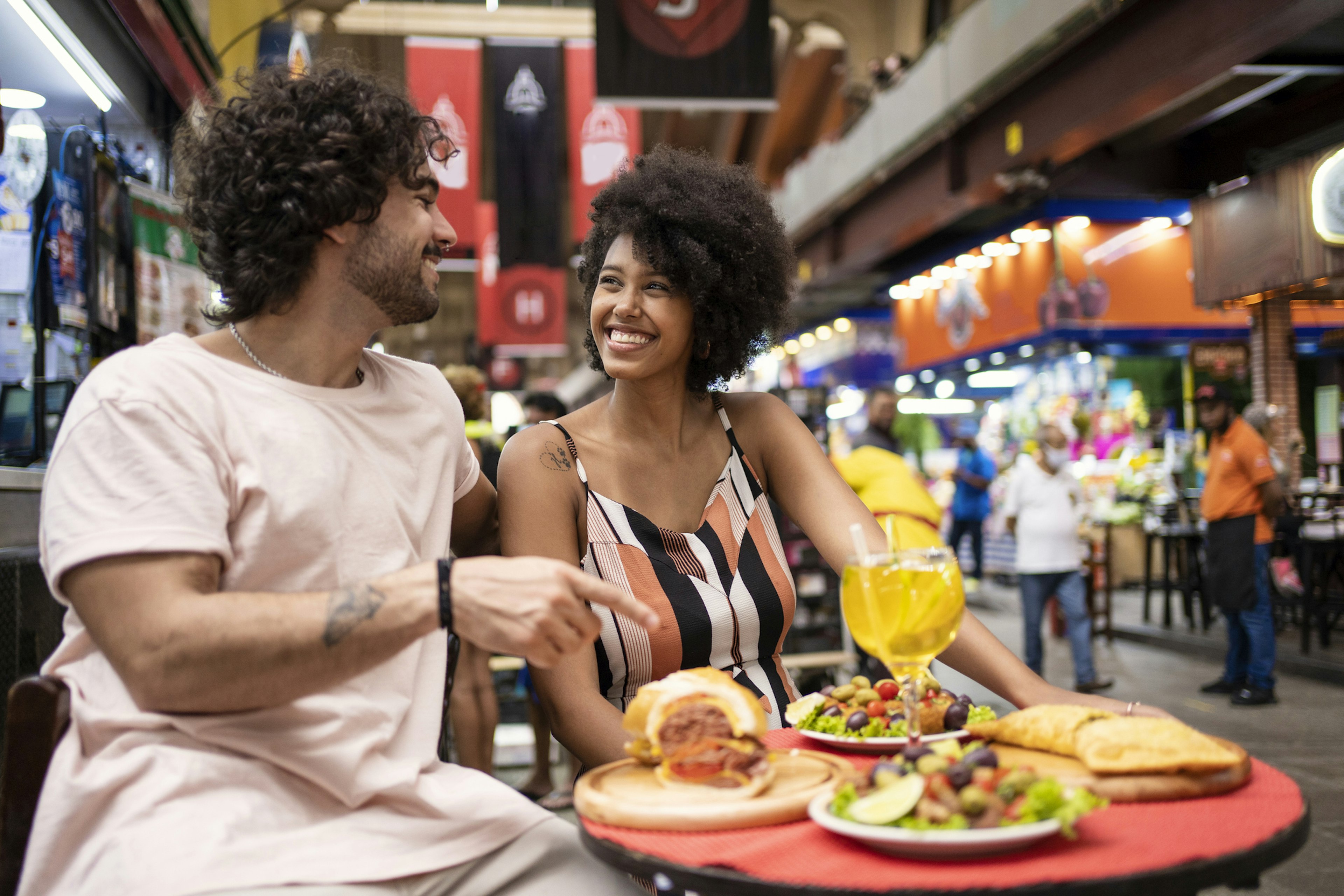 A woman and a man eating traditional food in the municipal market of São Paulo