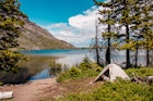 Photograph of a tent alongside a mountain lake on a mostly clear day in Glacier National Park.
1408457570