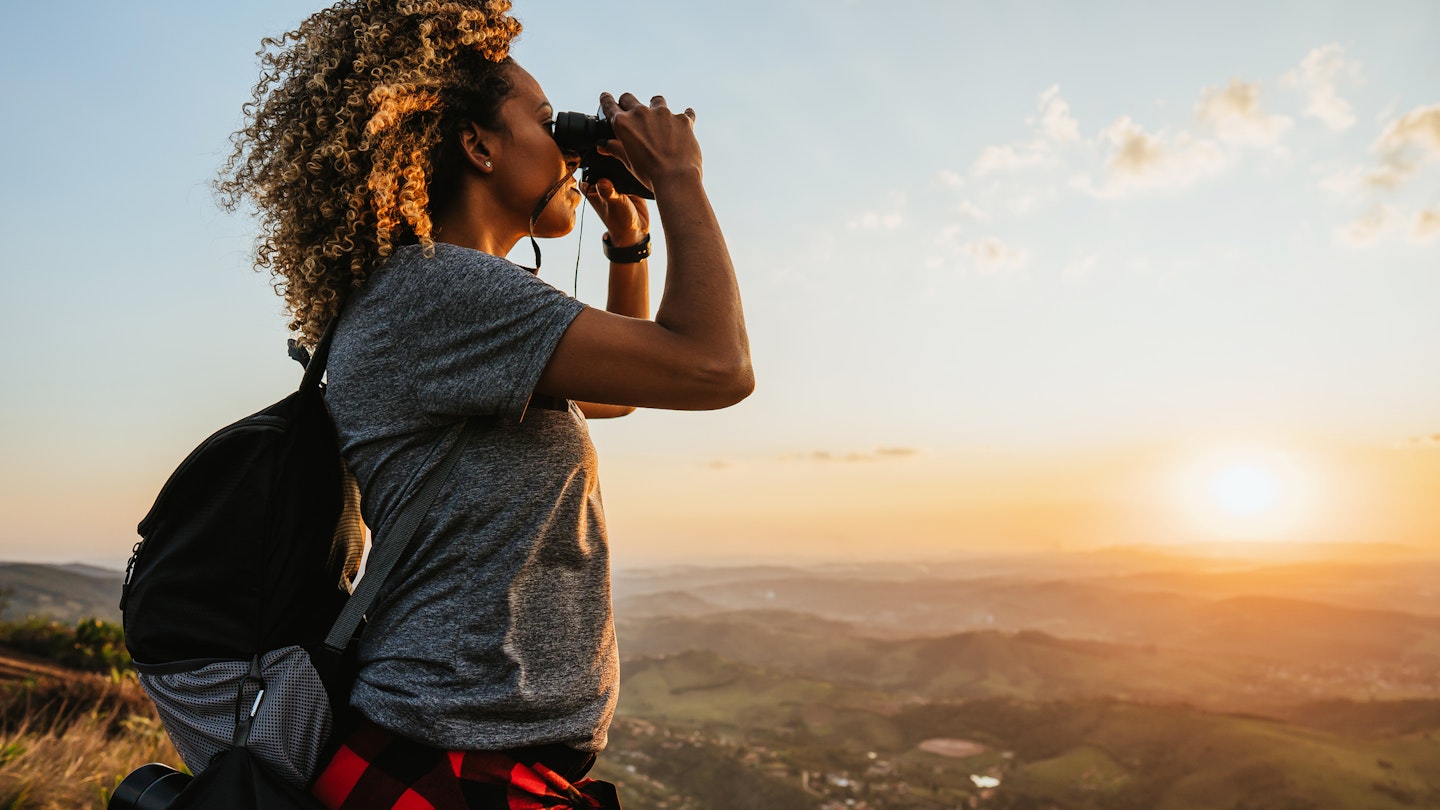A woman looking through binoculars on a hilltop in Brazil
