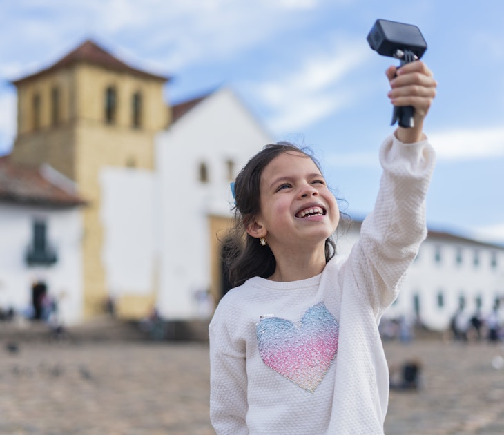 Latina girl with an average age of 7 years dressed comfortably is in the historic square of Villa de Leyva boyaca to which she traveled with her family taking a selfie with her gopro
1446044175
