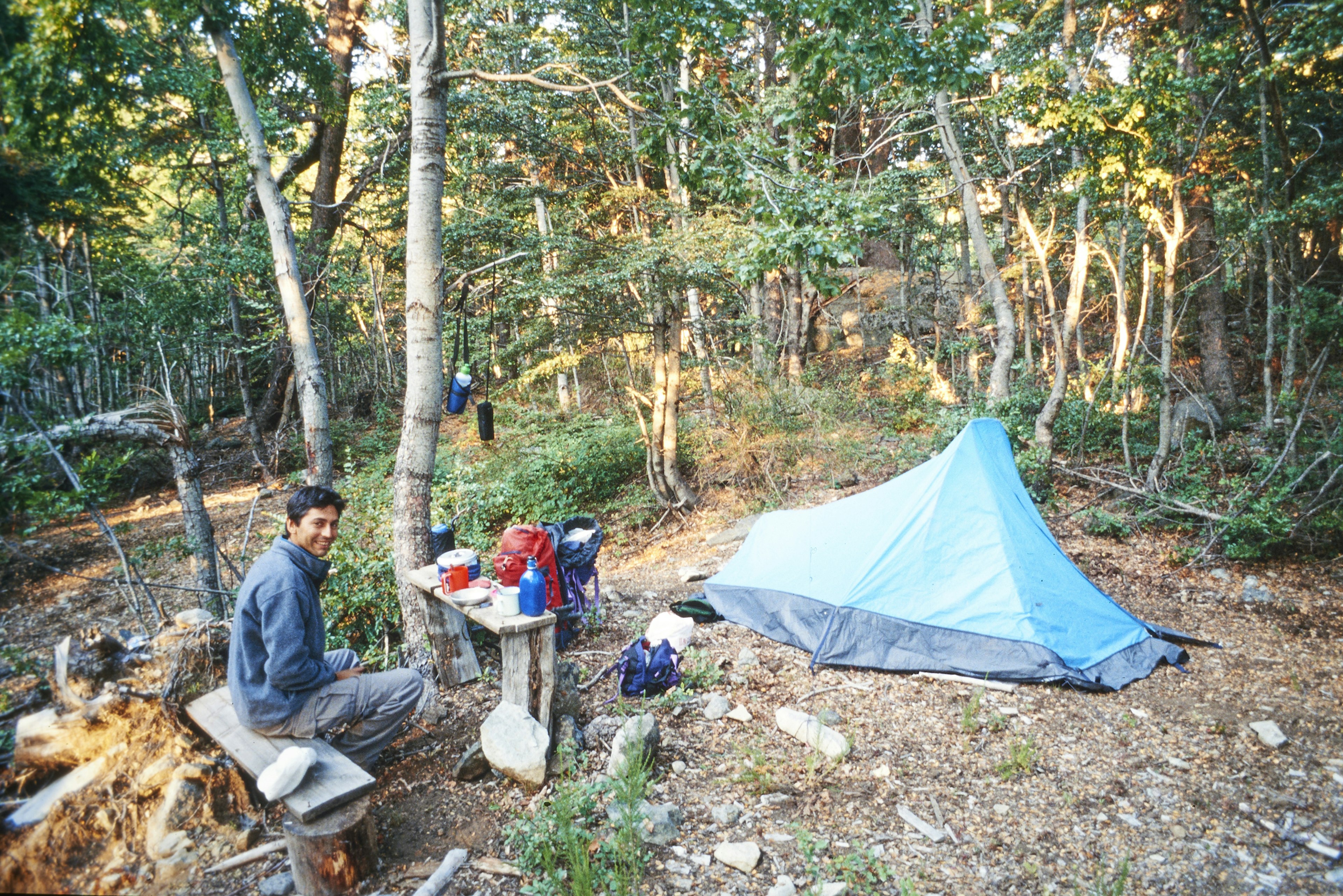 A young man smiles at the camera while resting at a camping site in Chile