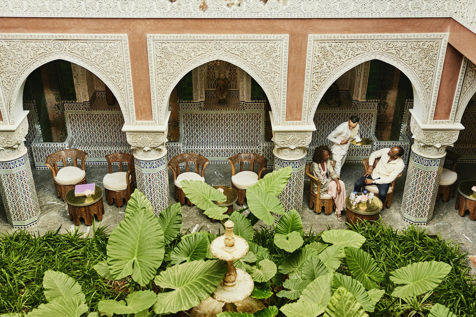 A couple is served mint tea by a waiter in the courtyard of a riad in Marrakesh, Morocco