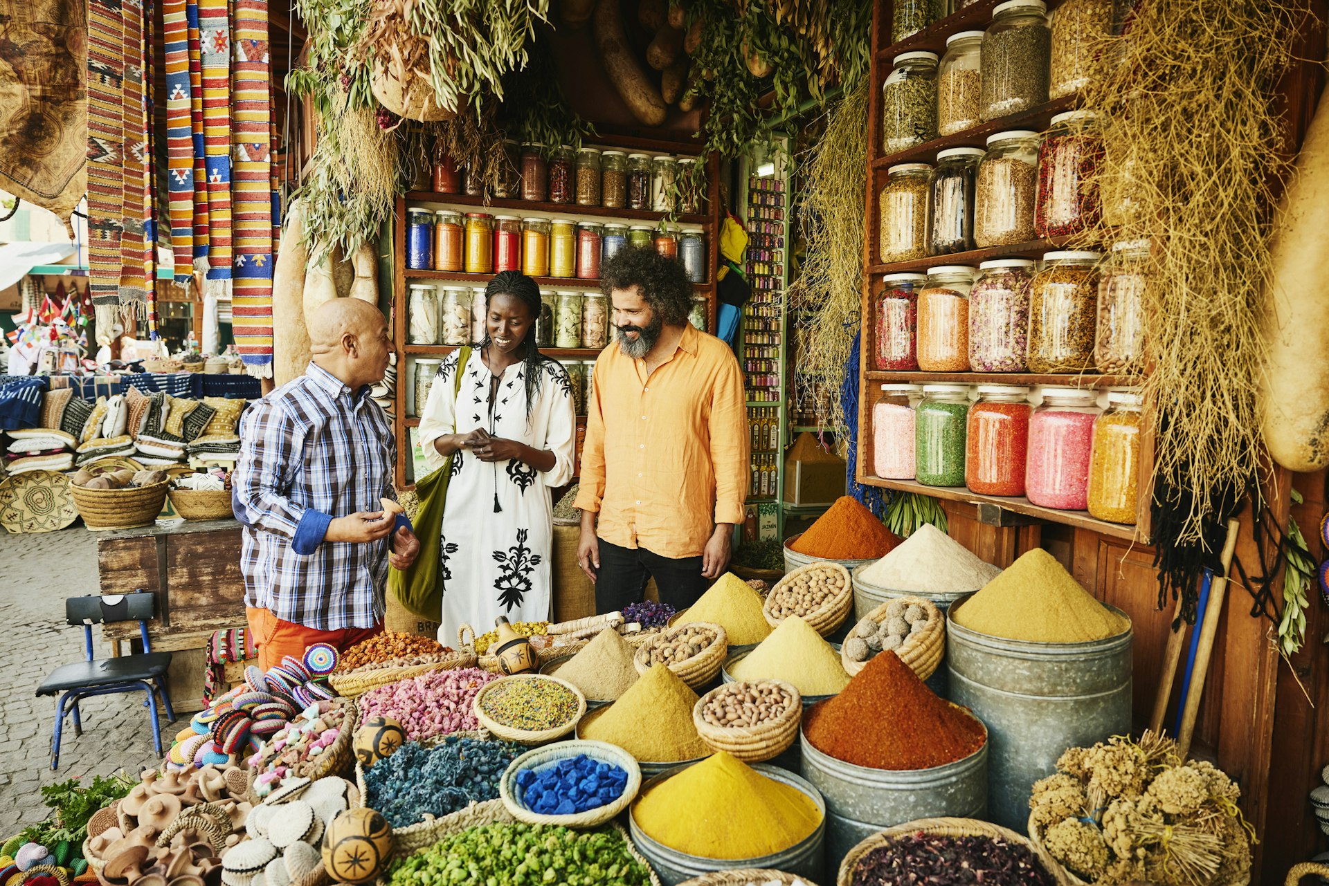 A couple talks to a shop owner while shopping in the markets of the Marrakesh medina in Morocco