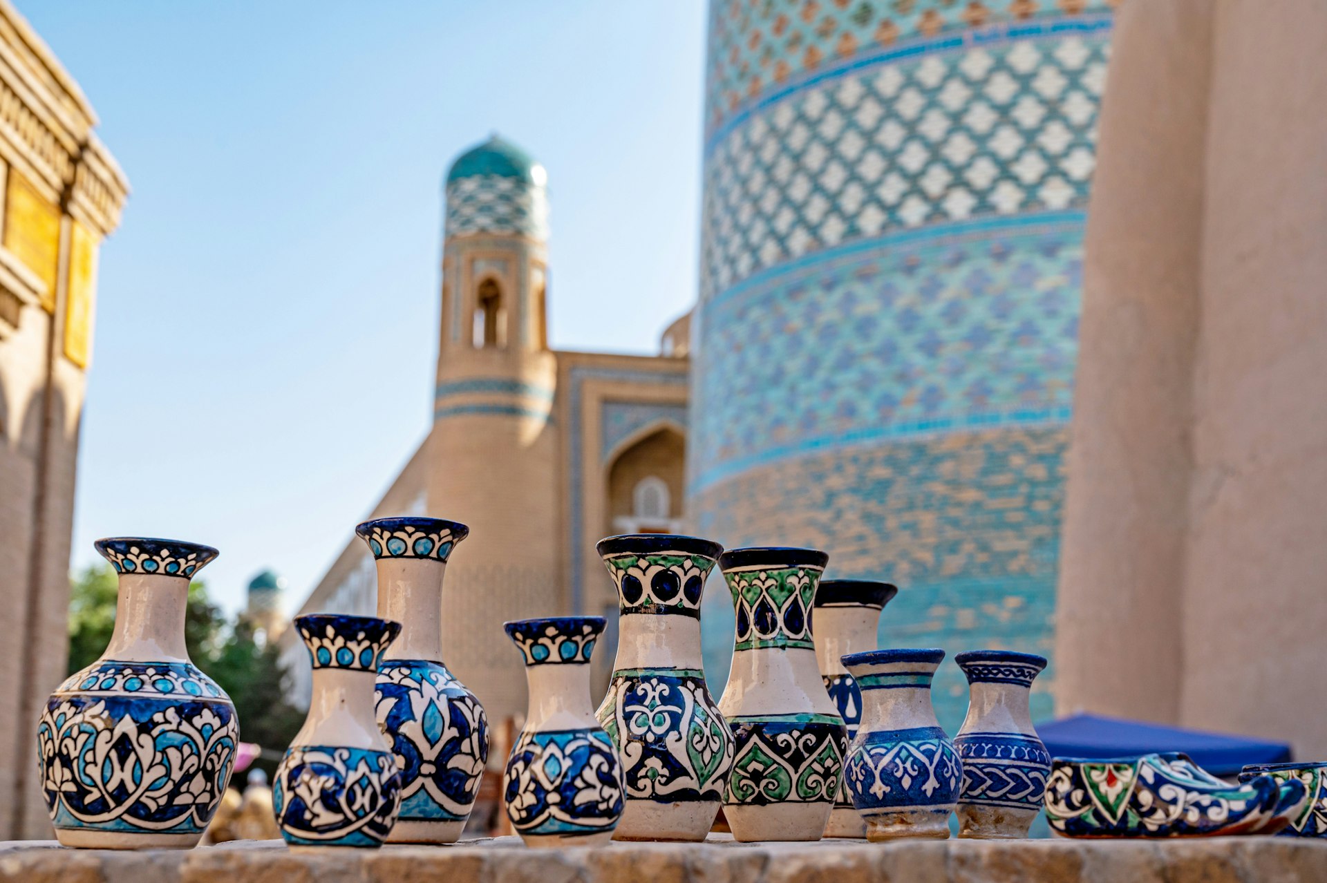 A row of small ceramic pots with intricate blue-and-white glazed patterns on them in front of a large tiled building