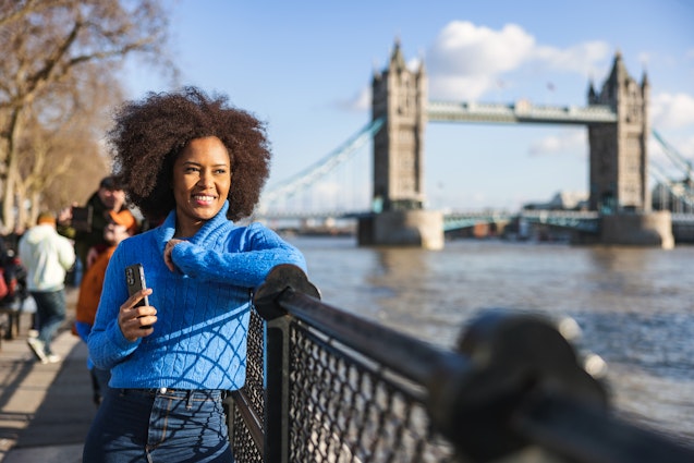 A Black woman looking at the River Thames in front of Tower Bridge