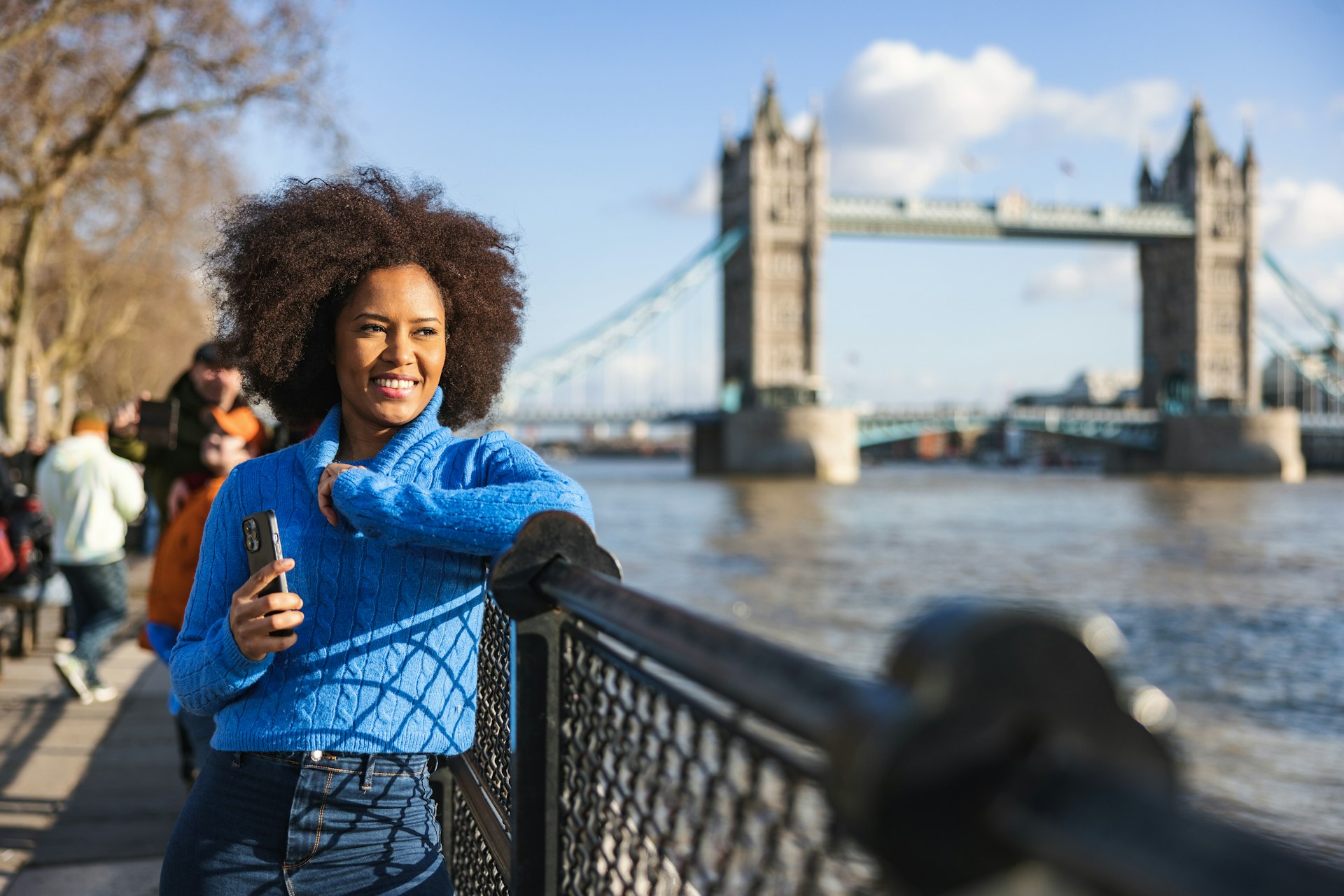A Black woman looking at the River Thames in front of Tower Bridge