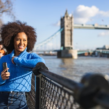 A Black woman looking at the River Thames in front of Tower Bridge