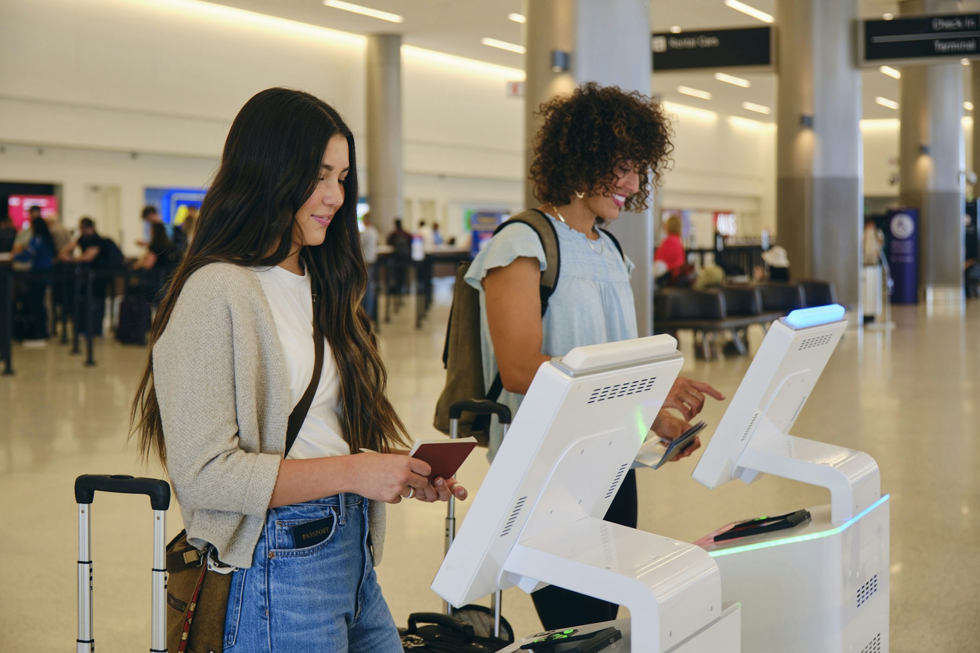 Two young women checking in at automated airport machines