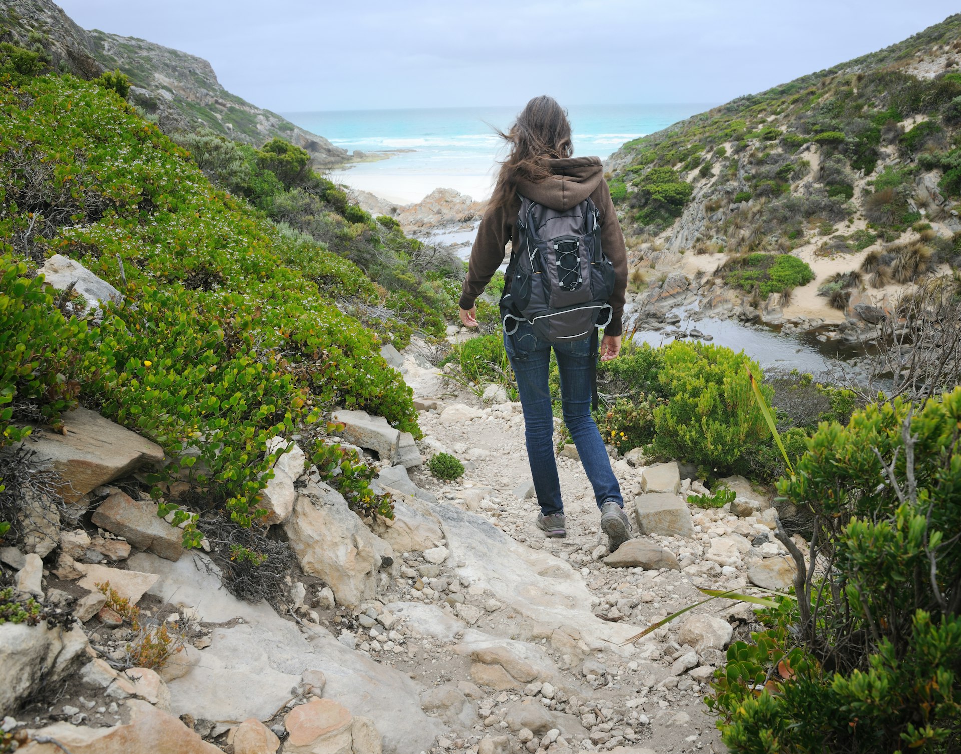 Beautiful woman hiking down to a secluded beach, Kangaroo Island, Australia