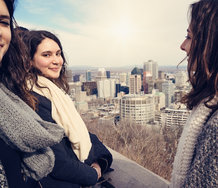 Group of three young women in their twenties on a belvedere, looking at a cityscape. They are all wearing warm clothes and big wool scarves. This was taken in Montreal, Quebec, Canada, on a spring windy and sunny day. Horizontal waist up shot outdoors.
471292888
People Traveling, Tourism, Women, Three People, City Life, Scarf, 20s, Smiling, Connection, Friendship, Lifestyles, Urban Scene, Outdoors, Waist Up, Looking At Camera, Horizontal, People, Montreal, Quebec, Canada, Wind, Cityscape, Sunny
A group of women friends looking down on Montréal from the top of the hill in Parc du Mont-Royal.