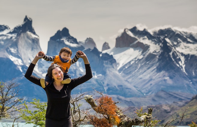 Happy mother and son enjoying the outdoors in Torres del Paine National Park, Patagonia, Chile, with the famous Torres del Paine mountains in the background.