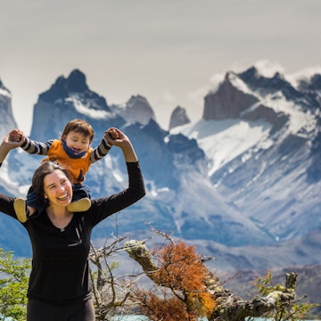 Happy mother and son enjoying the outdoors in Torres del Paine National Park, Patagonia, Chile, with the famous Torres del Paine mountains in the background.