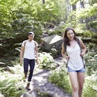 A woman and a man hiking along a forest path in NY state.