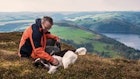 Man and his dog enjoying a rest after climbing a mountain in Wales, with a dramatic view overlooking Llyn Clewedog Reservoir.
592041107