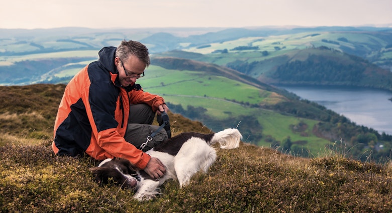 Man and his dog enjoying a rest after climbing a mountain in Wales, with a dramatic view overlooking Llyn Clewedog Reservoir.
592041107