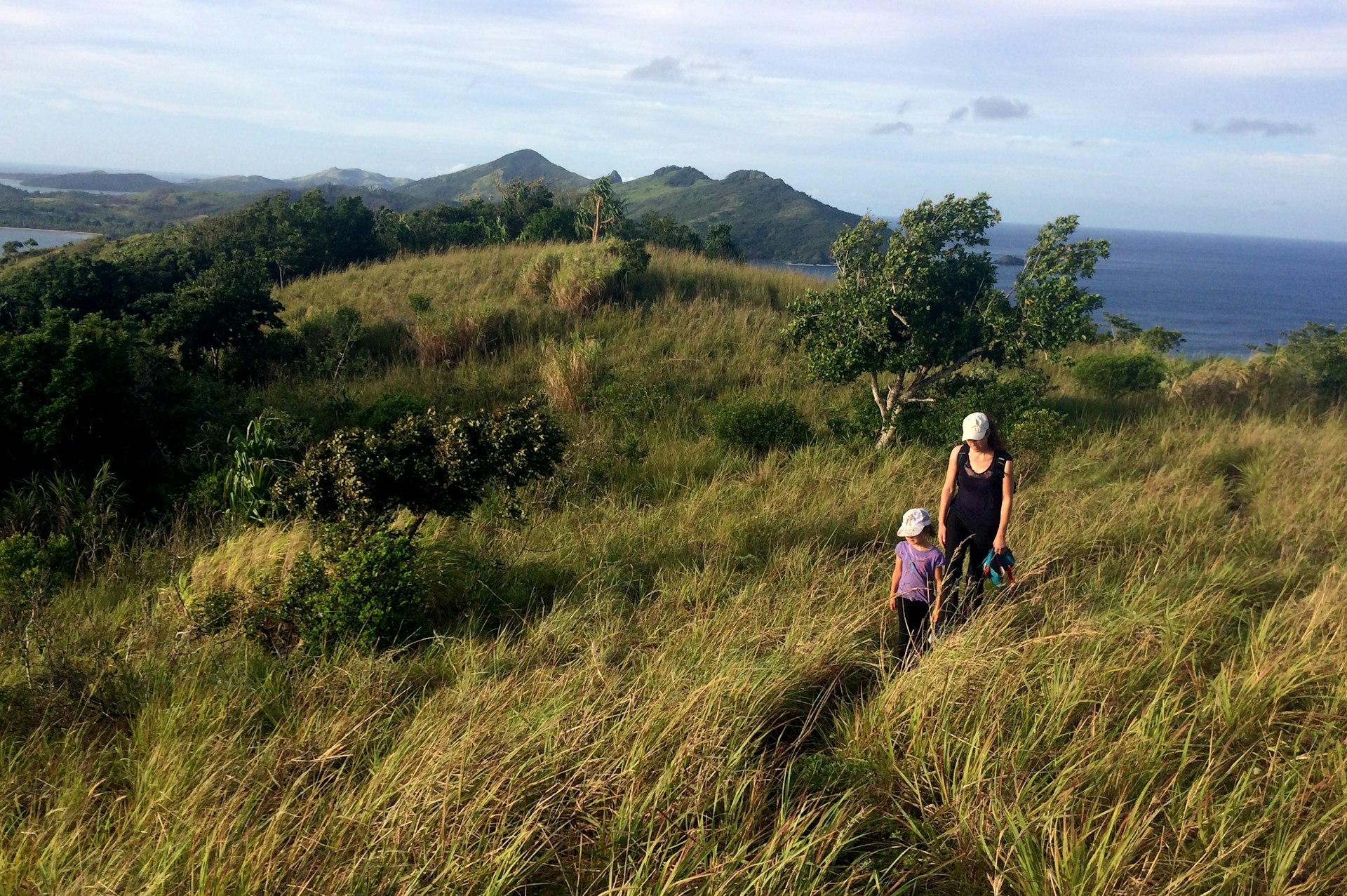 A mother and child hiking through the grass on one of the Yasawa Islands, Fiji 