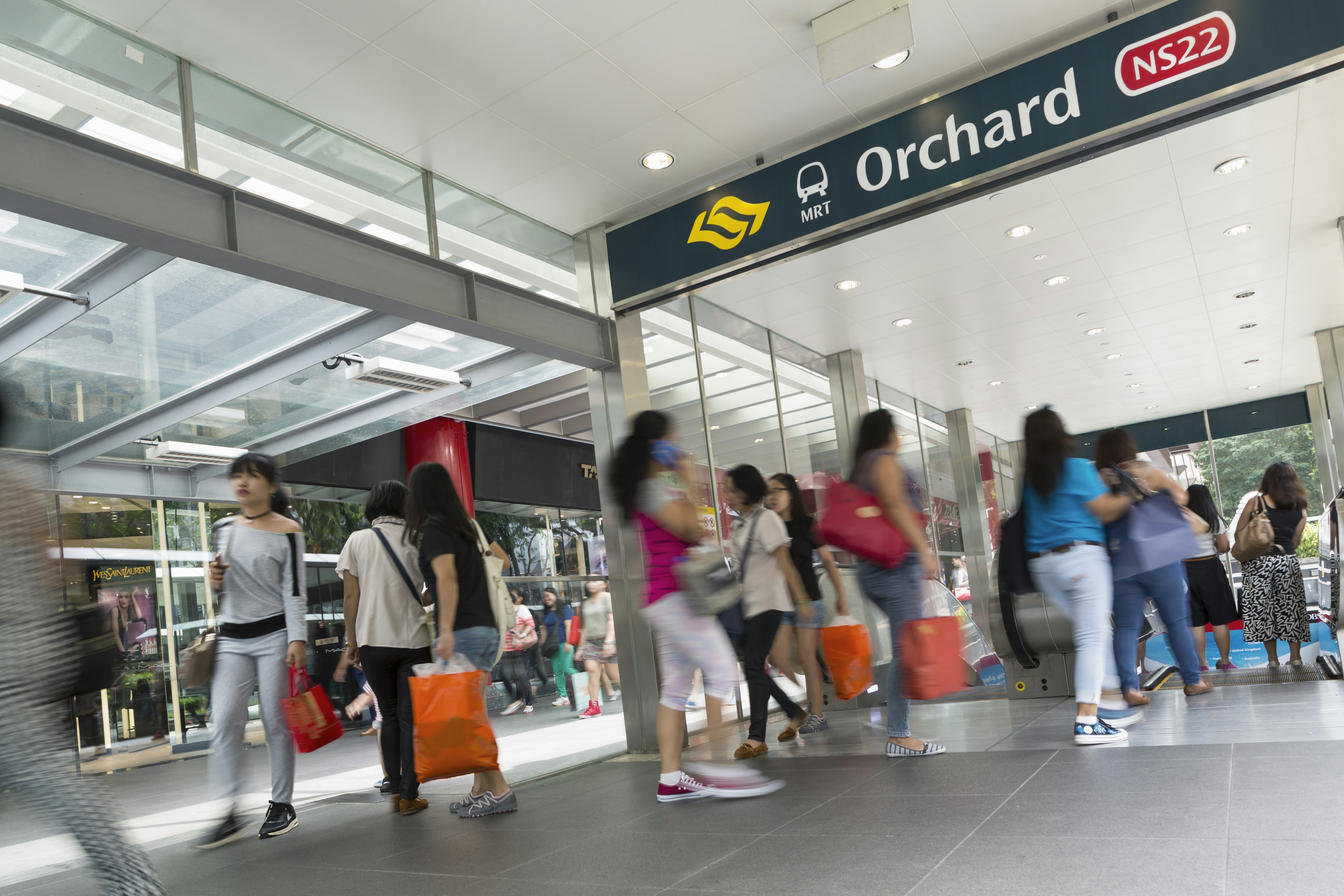 Groups of people move quickly through a public transit hub in Singapore