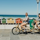 855782736
Two friends riding a tandem bike on the boardwalk in Cape Town, South Africa