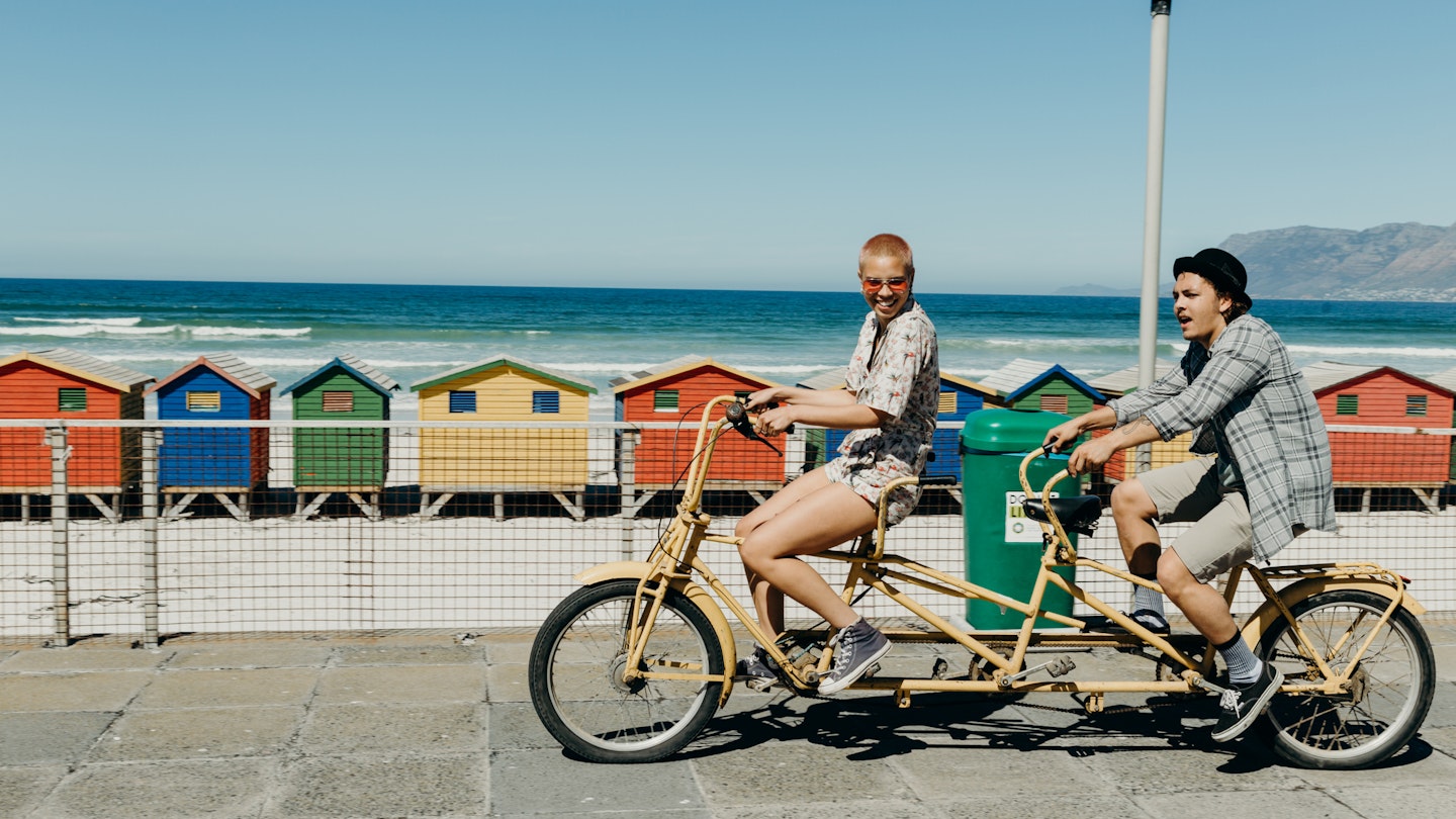 855782736
Two friends riding a tandem bike on the boardwalk in Cape Town, South Africa